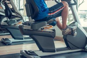 joven usando una bicicleta estática en un gimnasio interior foto