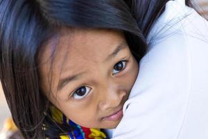 A little Asian girl hugs his mother with love and warmth between mother and child. photo