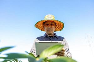 Smart Farmer An Asian man uses a tablet to analyze the crops he grows in his farm during the day. photo