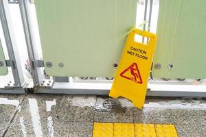 Yellow Caution slippery wet floor sign on the wet ground photo