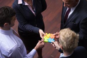 top view of business people group assembling jigsaw puzzle photo