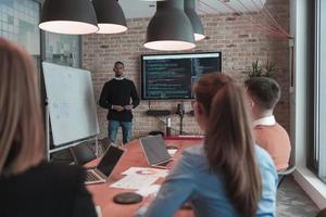 el líder da una presentación de negocios en una reunión de la conferencia de la oficina, el mentor del entrenador de negocios explica el gráfico a bordo del taller de capacitación del grupo corporativo en la sala de juntas. enfoque selectivo foto