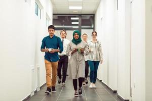 Multi-ethnic startup business team walking through the hallway of the building while coming back from a coffee break photo