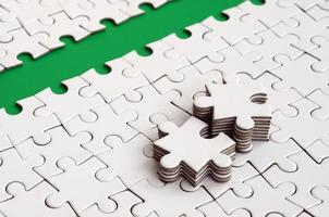 The green path is laid on the platform of a white folded jigsaw puzzle. The missing elements of the puzzle are stacked nearby. Texture image with space for text photo