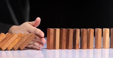 Business woman hand stop domino continuous tipping risk. Financial crisis and economic decline stop problem falling effect with success strategy management and solving opportunity concept, copy space photo