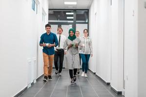 Multi-ethnic startup business team walking through the hallway of the building while coming back from a coffee break photo
