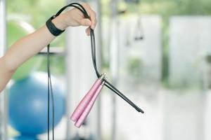 mano de mujer sosteniendo cuerda de saltar rosa en el gimnasio. concepto de fitness y deporte. foto