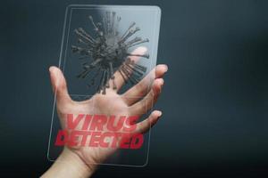 mano sosteniendo y mostrando el virus detectado en el dispositivo de tableta. COVID-19 foto