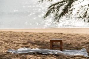 Wooden chair and white towel on the beach, ocean background. photo