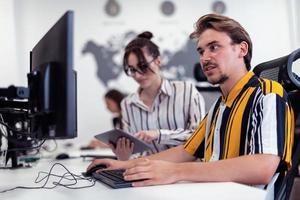 Business couple working together on project using tablet and desktop computer at modern open plan startup office. Selective focus photo