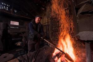 joven herrero tradicional trabajando con fuego abierto foto