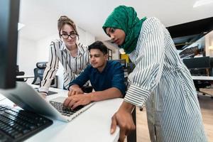 Multiethnic startup business team Arabian woman wearing a hijab on meeting in modern open plan office interior brainstorming, working on laptop and desktop computer. Selective focus photo