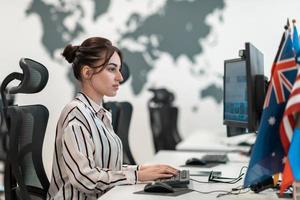 Casual business woman working on desktop computer in modern open plan startup office interior. Selective focus photo