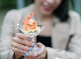 Grilled shrimp with cocktail sauce in woman hand. photo