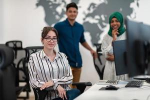 Multiethnic startup business team Arabian woman wearing a hijab on meeting in modern open plan office interior brainstorming, working on laptop and desktop computer. Selective focus photo