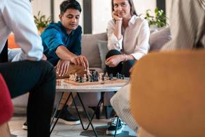 Multiethnic group of business people playing chess while having a break in relaxation area at modern startup office. Selective focus photo