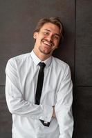 Portrait of startup businessman in a white shirt with a black tie standing in front of gray wall outside photo