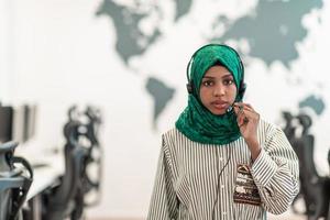 mujer musulmana con pañuelo verde hiyab representante del cliente mujer de negocios con auriculares de teléfono ayudando y apoyando en línea con el cliente en un centro de llamadas moderno foto