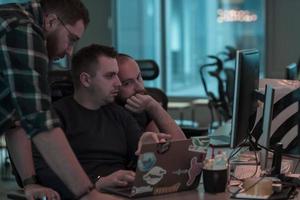 A photo of three men staring intently at a computer while sitting in a modern office. Selective focus