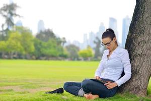 Beautiful young woman with  tablet in park photo