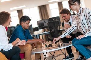 Multiethnic group of business people playing chess while having a break in relaxation area at modern startup office photo