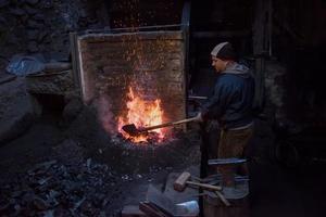 joven herrero tradicional trabajando con fuego abierto foto