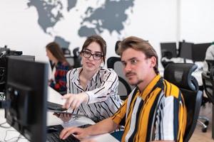 Business couple working together on project using tablet and desktop computer at modern open plan startup office. Selective focus photo