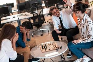 Multiethnic group of business people playing chess while having a break in relaxation area at modern startup office photo