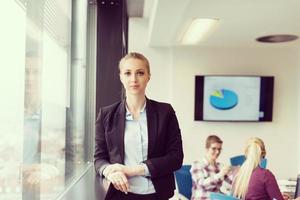 portrait of young business woman at office with team on meeting in background photo