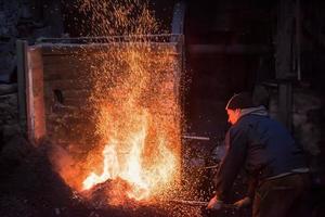 joven herrero tradicional trabajando con fuego abierto foto