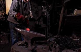 blacksmith manually forging the molten metal photo