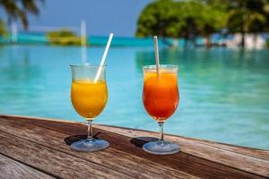 dos cócteles en un resort de playa tropical de lujo. vacaciones en pareja, vacaciones de viaje, piscina de la isla de verano con bebida, estilo de vida de ocio en el bar de la playa en el suelo de madera. piscina al aire libre y bebidas foto