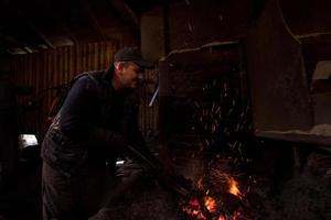 joven herrero tradicional trabajando con fuego abierto foto