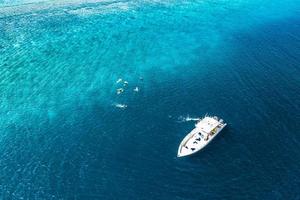 Beautiful turquoise ocean water and boat, view aerial drone seascape. Tropical sea waves, amazing aerial coral reef, lagoon. People recreational outdoor activity, swimming, snorkeling, diving tourism photo