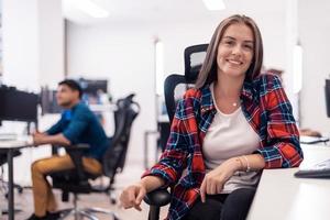 mujer de negocios informal que trabaja en una computadora de escritorio en el moderno interior de la oficina de inicio de planta abierta. enfoque selectivo foto