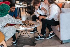 Multiethnic group of business people playing chess while having a break in relaxation area at modern startup office photo