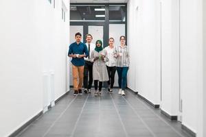 Multi-ethnic startup business team walking through the hallway of the building while coming back from a coffee break photo