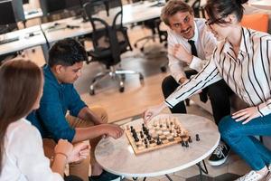 Multiethnic group of business people playing chess while having a break in relaxation area at modern startup office photo