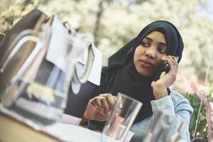 mujer africana que usa un teléfono inteligente con ropa islámica tradicional foto