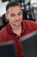 Casual business man working on desktop computer in modern open plan startup office interior. Selective focus photo