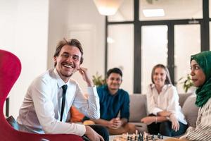 Multiethnic group of business people playing chess while having a break in relaxation area at modern startup office. photo