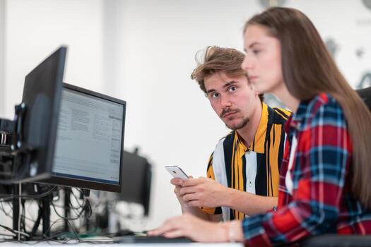 Business couple working together on project using tablet and desktop computer at modern open plan startup office. Selective focus photo