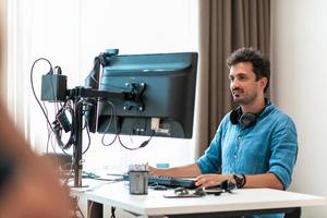 Casual man working on desktop computer in modern open plan startup office interior. Selective focus photo