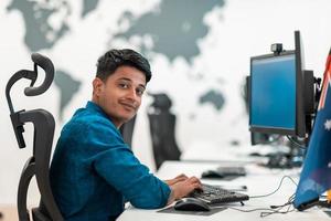 Casual business man working on desktop computer in modern open plan startup office interior. Selective focus photo