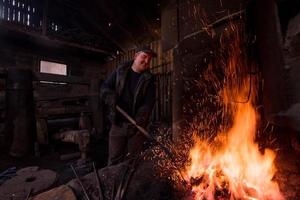 joven herrero tradicional trabajando con fuego abierto foto