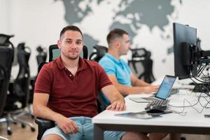 Group of Casual business man working on desktop computer in modern open plan startup office interior. Selective focus photo