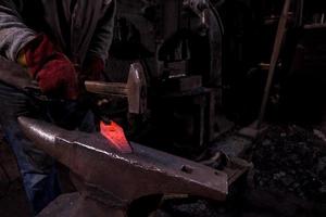 blacksmith manually forging the molten metal photo