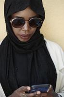 african  woman using smartphone wearing traditional islamic clothes photo