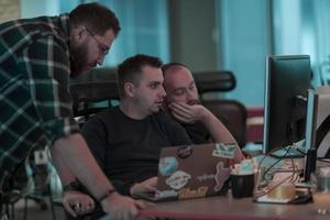 A photo of three men staring intently at a computer while sitting in a modern office. Selective focus