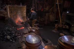 joven herrero tradicional trabajando con fuego abierto foto